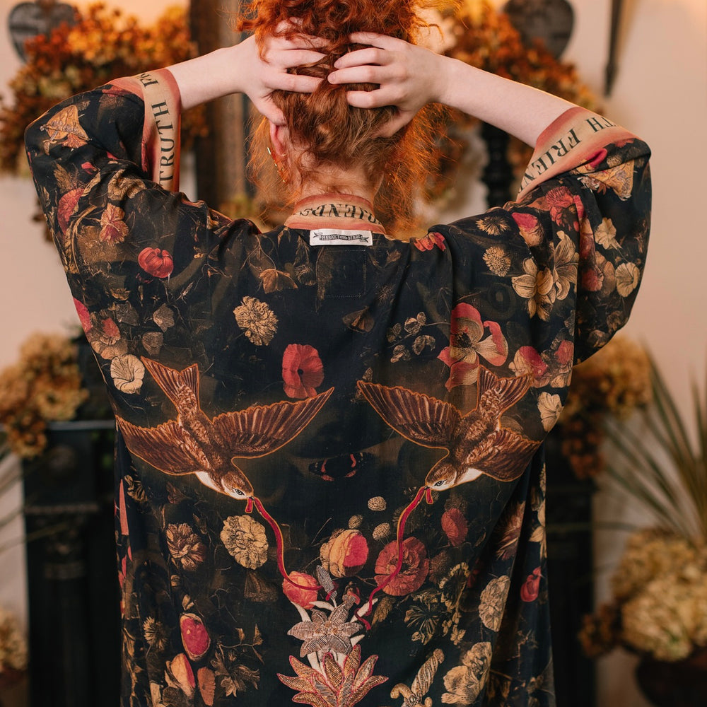 
                  
                    Model wearing a full-length bamboo-viscose duster featuring a collage of antique artwork with romance, loyalty, and old-world beauty - Market of Stars
                  
                