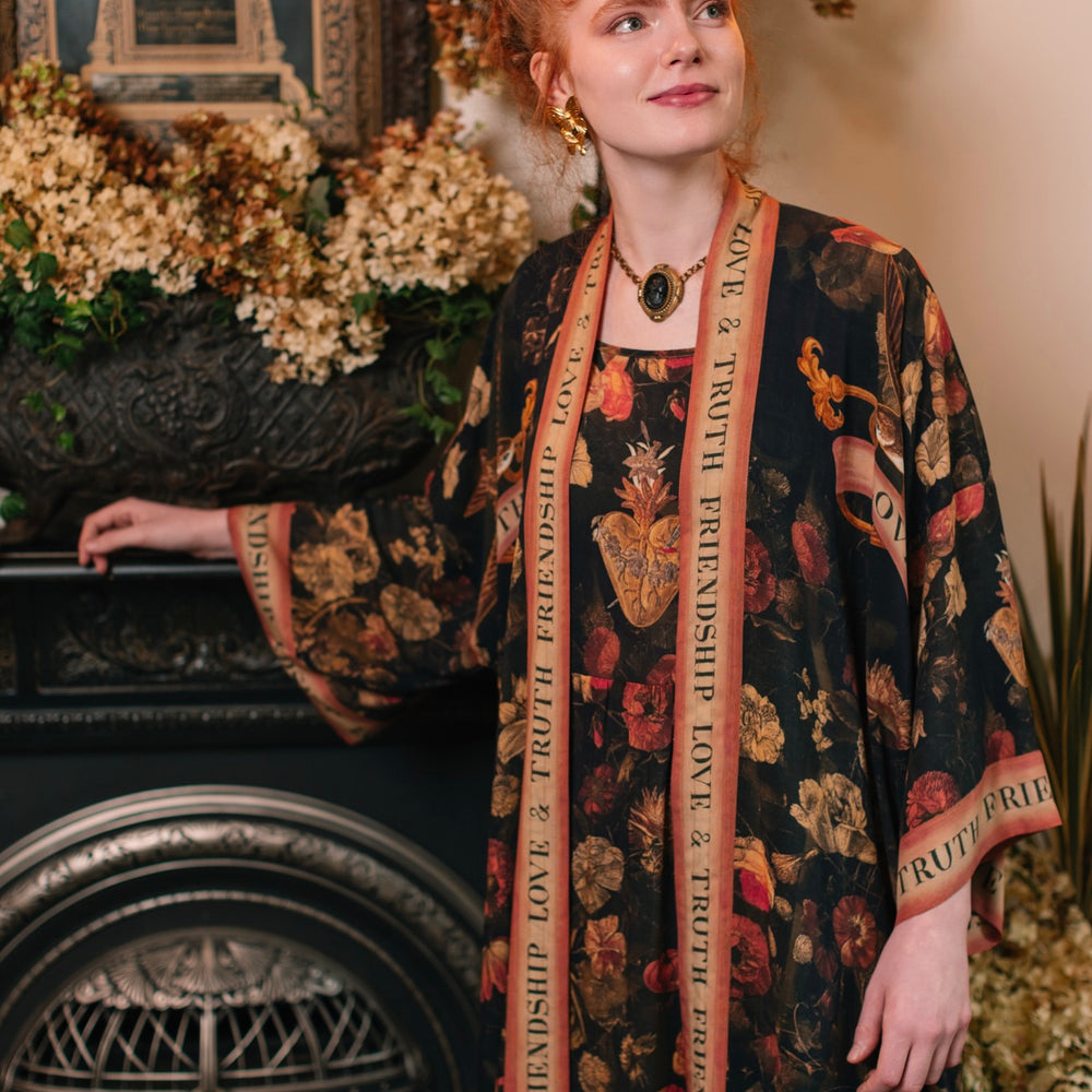 
                  
                    Model wearing a full-length bamboo-viscose duster featuring a collage of antique artwork with romance, loyalty, and old-world beauty - Market of Stars
                  
                