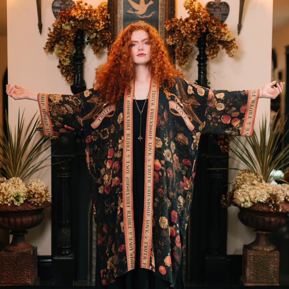 
                  
                    Model wearing a full-length bamboo-viscose duster featuring a collage of antique artwork with romance, loyalty, and old-world beauty - Market of Stars
                  
                