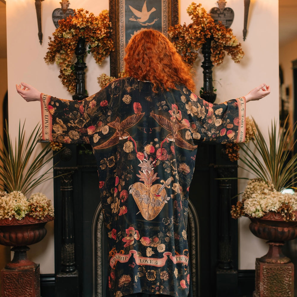
                  
                    Model wearing a full-length bamboo-viscose duster featuring a collage of antique artwork with romance, loyalty, and old-world beauty - Market of Stars
                  
                