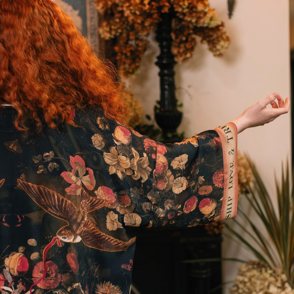 
                  
                    Model wearing a full-length bamboo-viscose duster featuring a collage of antique artwork with romance, loyalty, and old-world beauty - Market of Stars
                  
                