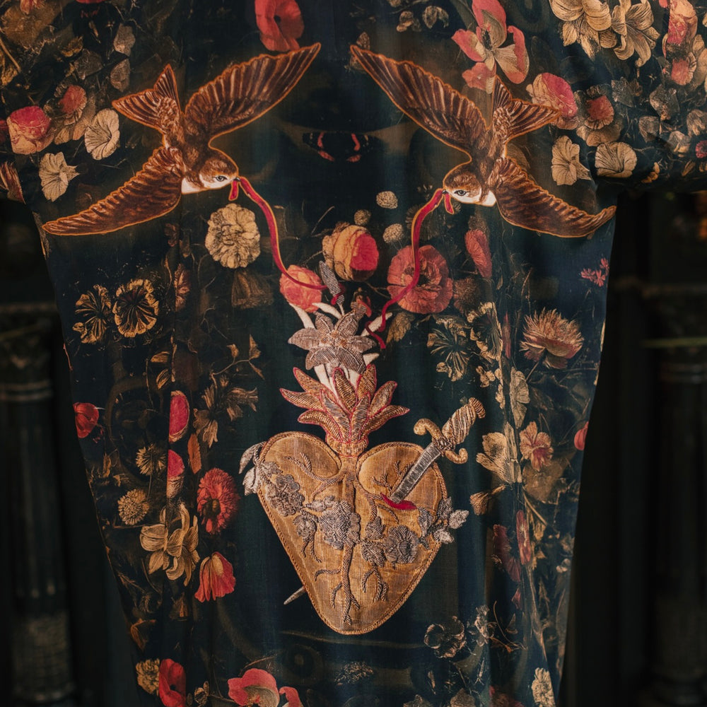 
                  
                    Model wearing a full-length bamboo-viscose duster featuring a collage of antique artwork with romance, loyalty, and old-world beauty - Market of Stars
                  
                