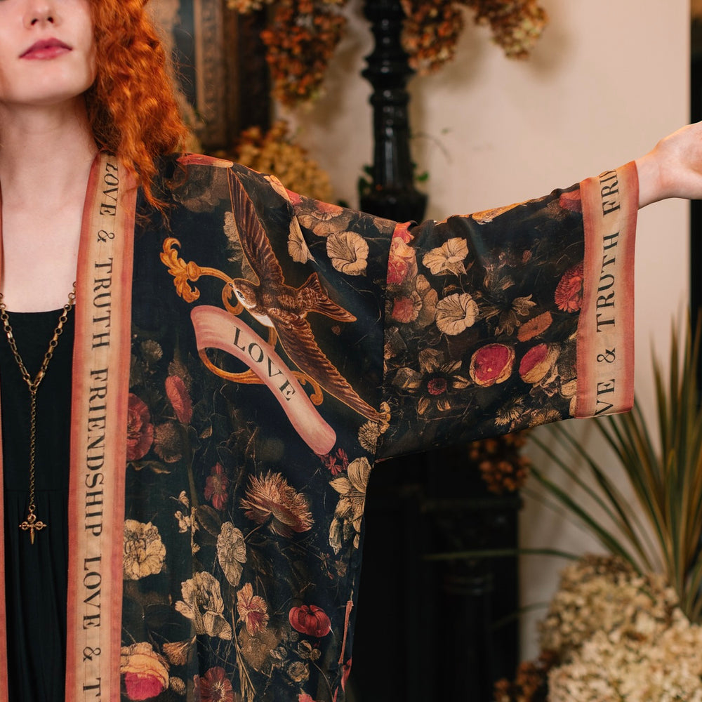 
                  
                    Model wearing a full-length bamboo-viscose duster featuring a collage of antique artwork with romance, loyalty, and old-world beauty - Market of Stars
                  
                