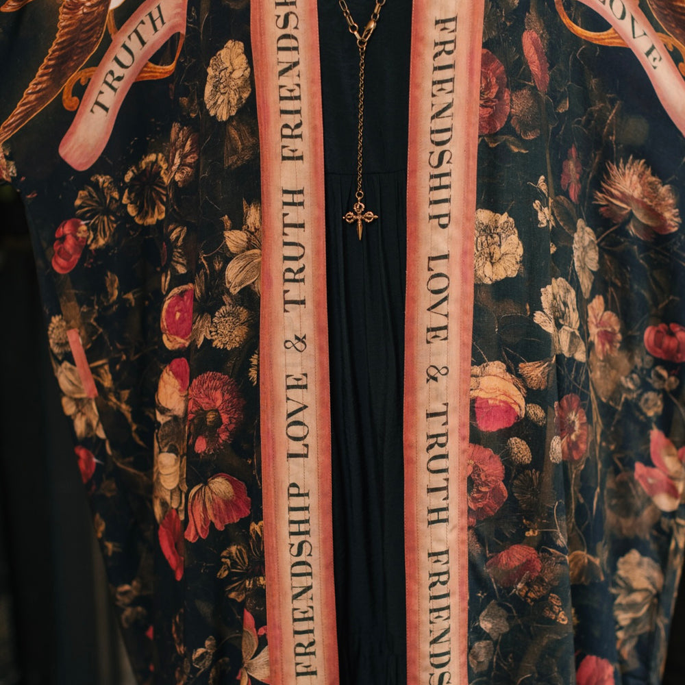 
                  
                    Model wearing a full-length bamboo-viscose duster featuring a collage of antique artwork with romance, loyalty, and old-world beauty - Market of Stars
                  
                