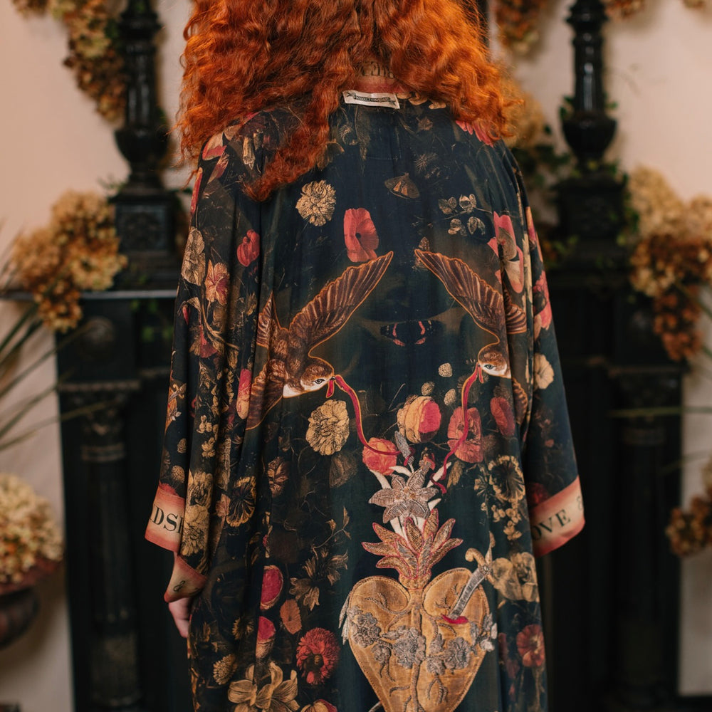 
                  
                    Model wearing a full-length bamboo-viscose duster featuring a collage of antique artwork with romance, loyalty, and old-world beauty - Market of Stars
                  
                