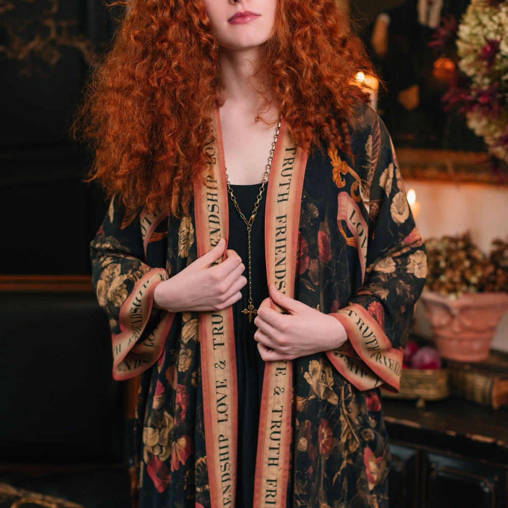 
                  
                    Model wearing a full-length bamboo-viscose duster featuring a collage of antique artwork with romance, loyalty, and old-world beauty - Market of Stars
                  
                