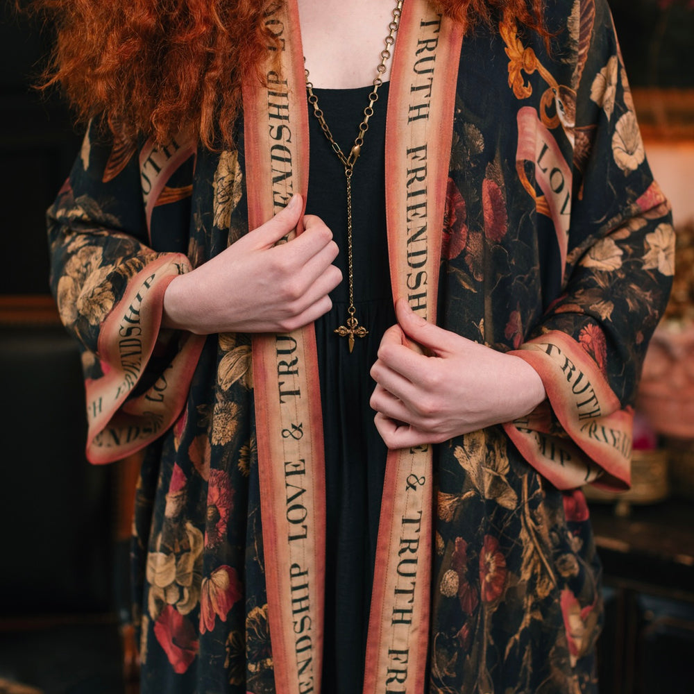 
                  
                    Model wearing a full-length bamboo-viscose duster featuring a collage of antique artwork with romance, loyalty, and old-world beauty - Market of Stars
                  
                