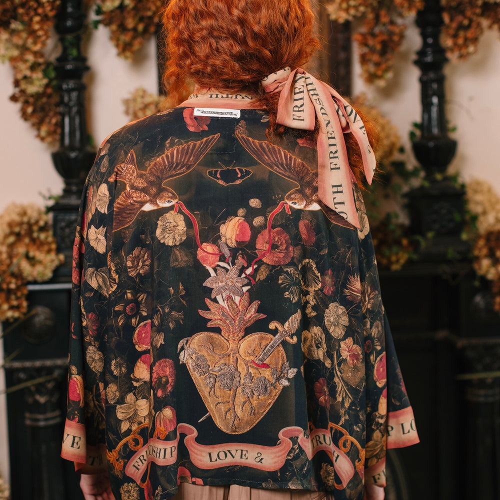 
                  
                    Model wearing a cropped-length bamboo-viscose duster featuring a collage of antique artwork with romance, loyalty, and old-world beauty - Market of Stars
                  
                