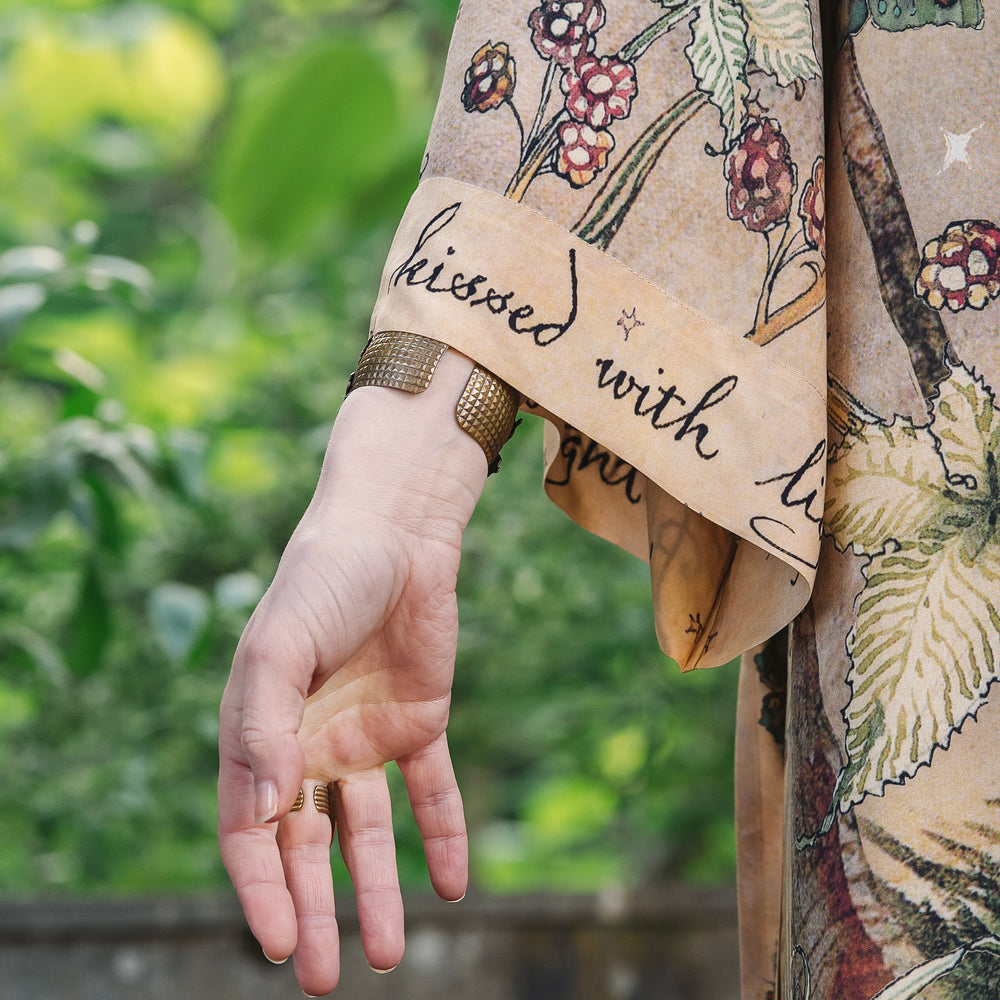 
                  
                    Model wearing an enchanting kimono duster robe featuring illustrations by Charles van Sandwyck's, crafted from airy bamboo-based viscose with a touch of whimsical magic - Market of Stars
                  
                