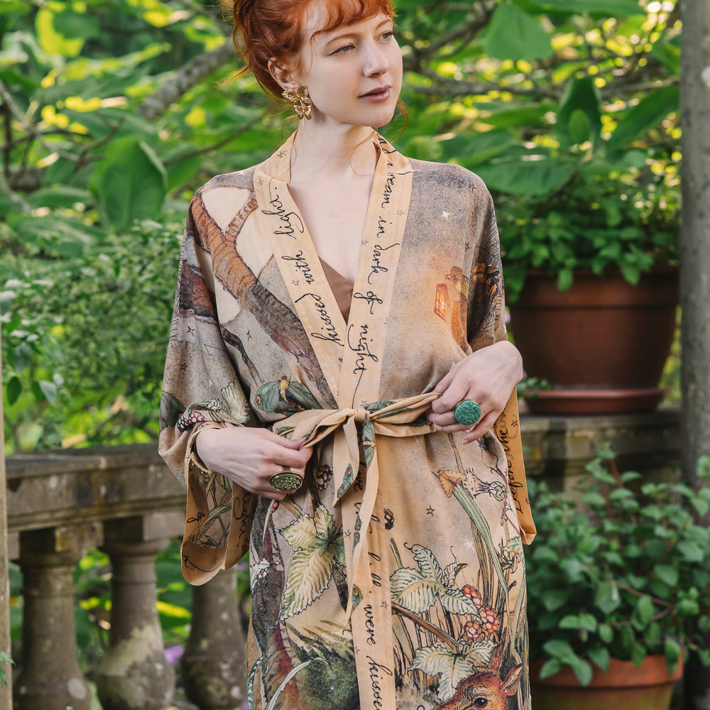 
                  
                    Model wearing an enchanting kimono duster robe featuring illustrations by Charles van Sandwyck's, crafted from airy bamboo-based viscose with a touch of whimsical magic - Market of Stars
                  
                
