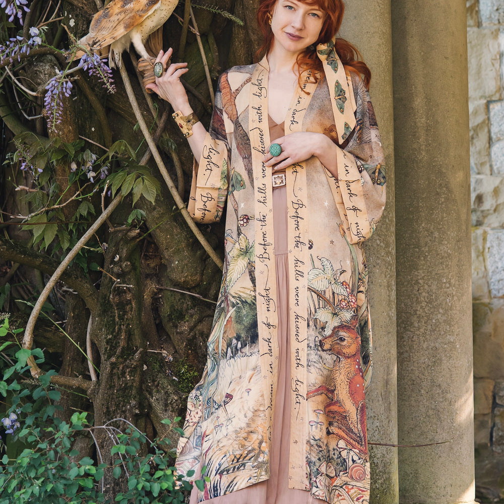 
                  
                    Model wearing an enchanting kimono duster robe featuring illustrations by Charles van Sandwyck's, crafted from airy bamboo-based viscose with a touch of whimsical magic - Market of Stars
                  
                