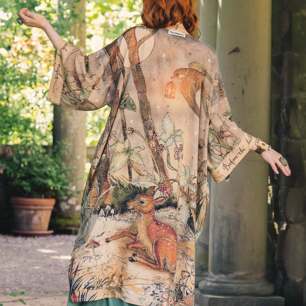
                  
                    Model wearing an enchanting kimono duster robe featuring illustrations by Charles van Sandwyck's, crafted from airy bamboo-based viscose with a touch of whimsical magic - Market of Stars
                  
                