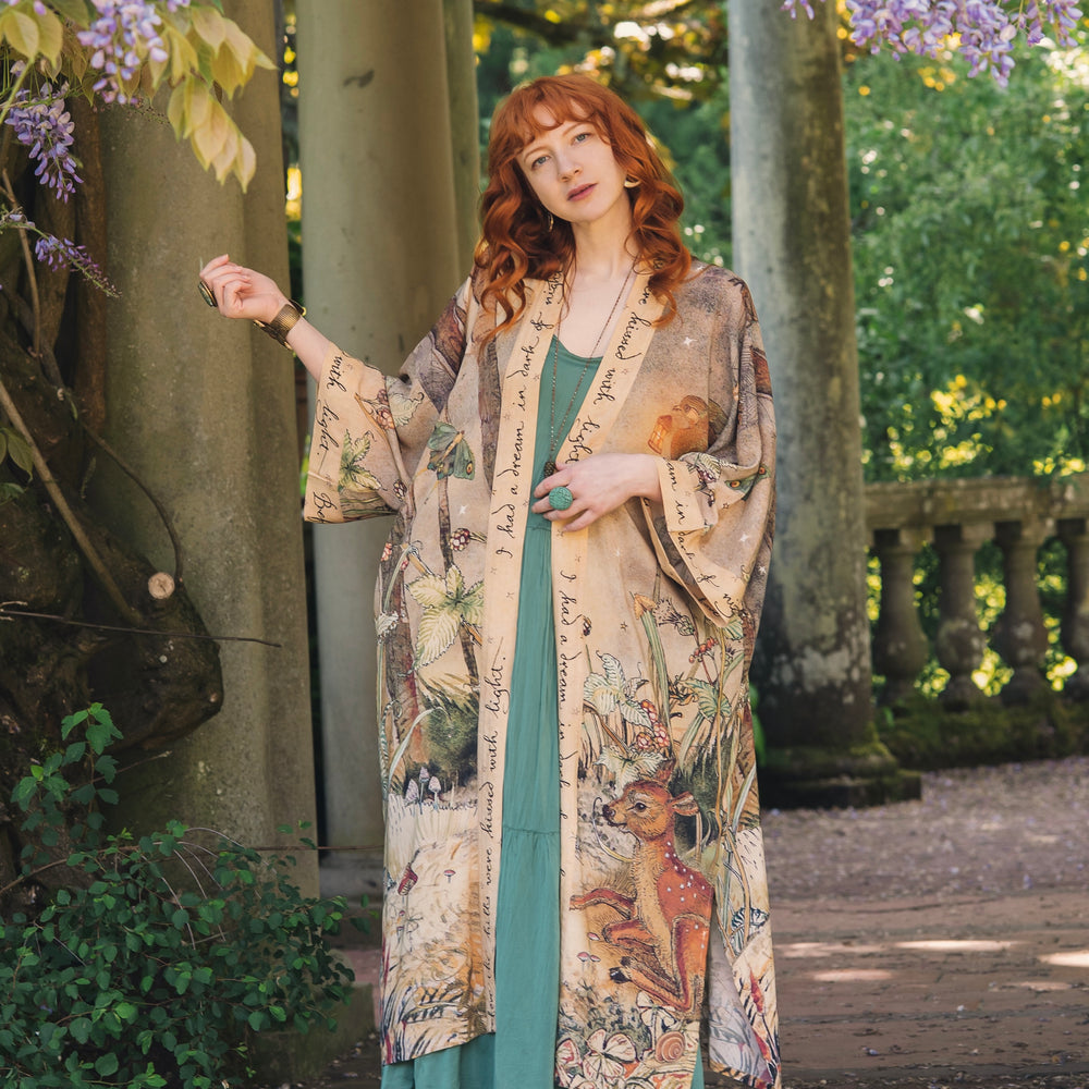 
                  
                    Model wearing an enchanting kimono duster robe featuring illustrations by Charles van Sandwyck's, crafted from airy bamboo-based viscose with a touch of whimsical magic - Market of Stars
                  
                