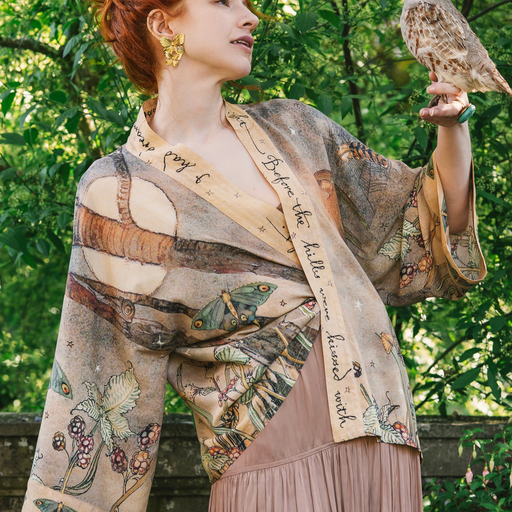 
                  
                    Model wearing an enchanting cropped kimono duster featuring illustrations by Charles van Sandwyck's, crafted from airy bamboo-based viscose with a touch of whimsical magic - Market of Stars
                  
                