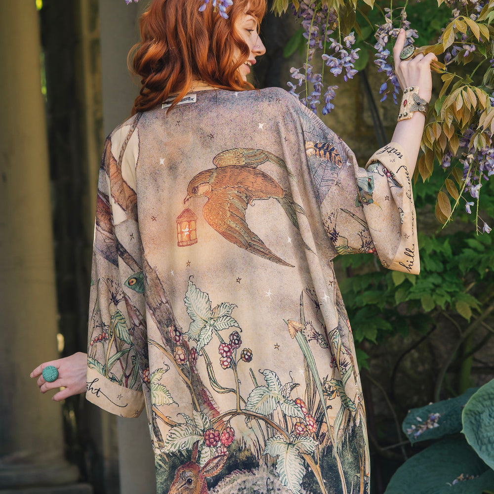 Model wearing an enchanting kimono duster robe featuring illustrations by Charles van Sandwyck's, crafted from airy bamboo-based viscose with a touch of whimsical magic - Market of Stars