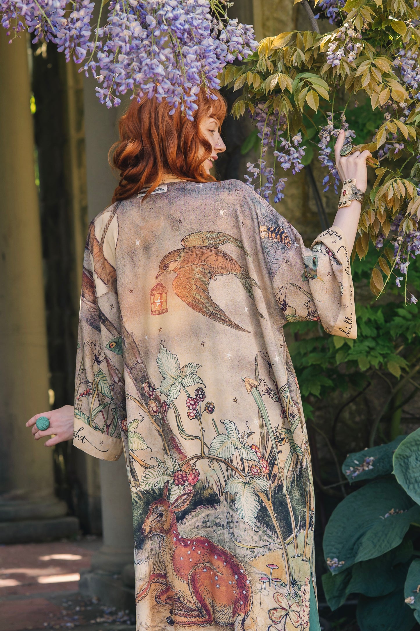 Model wearing an enchanting kimono duster robe featuring illustrations by Charles van Sandwyck's, crafted from airy bamboo-based viscose with a touch of whimsical magic - Market of Stars