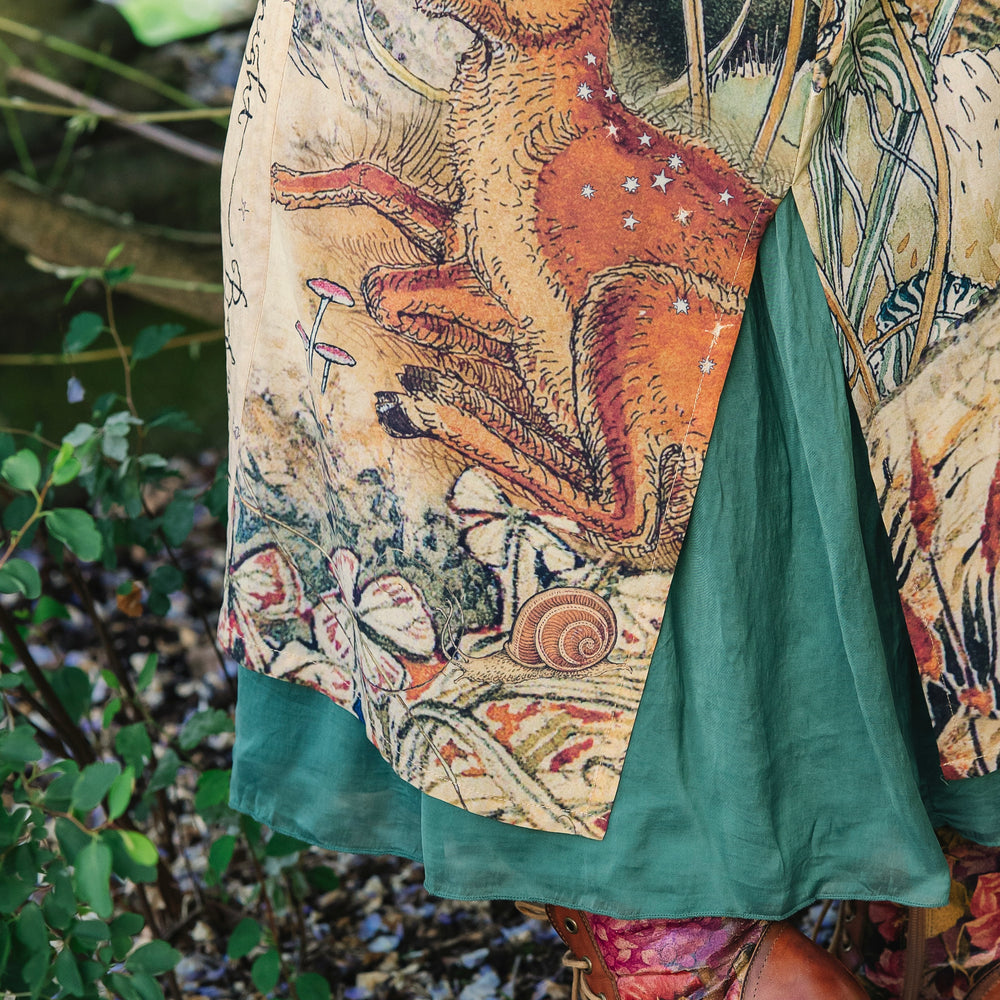 
                  
                    Model wearing an enchanting kimono duster robe featuring illustrations by Charles van Sandwyck's, crafted from airy bamboo-based viscose with a touch of whimsical magic - Market of Stars
                  
                