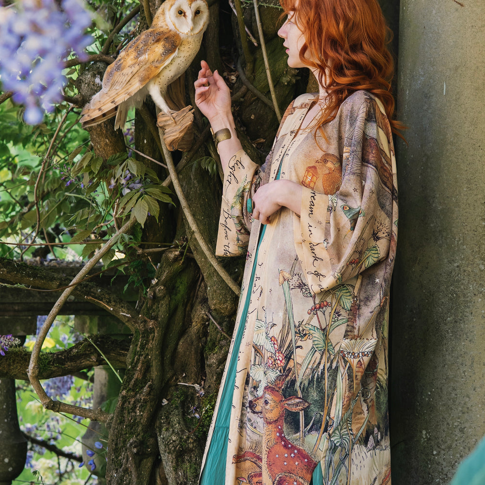 
                  
                    Model wearing an enchanting kimono duster robe featuring illustrations by Charles van Sandwyck's, crafted from airy bamboo-based viscose with a touch of whimsical magic - Market of Stars
                  
                