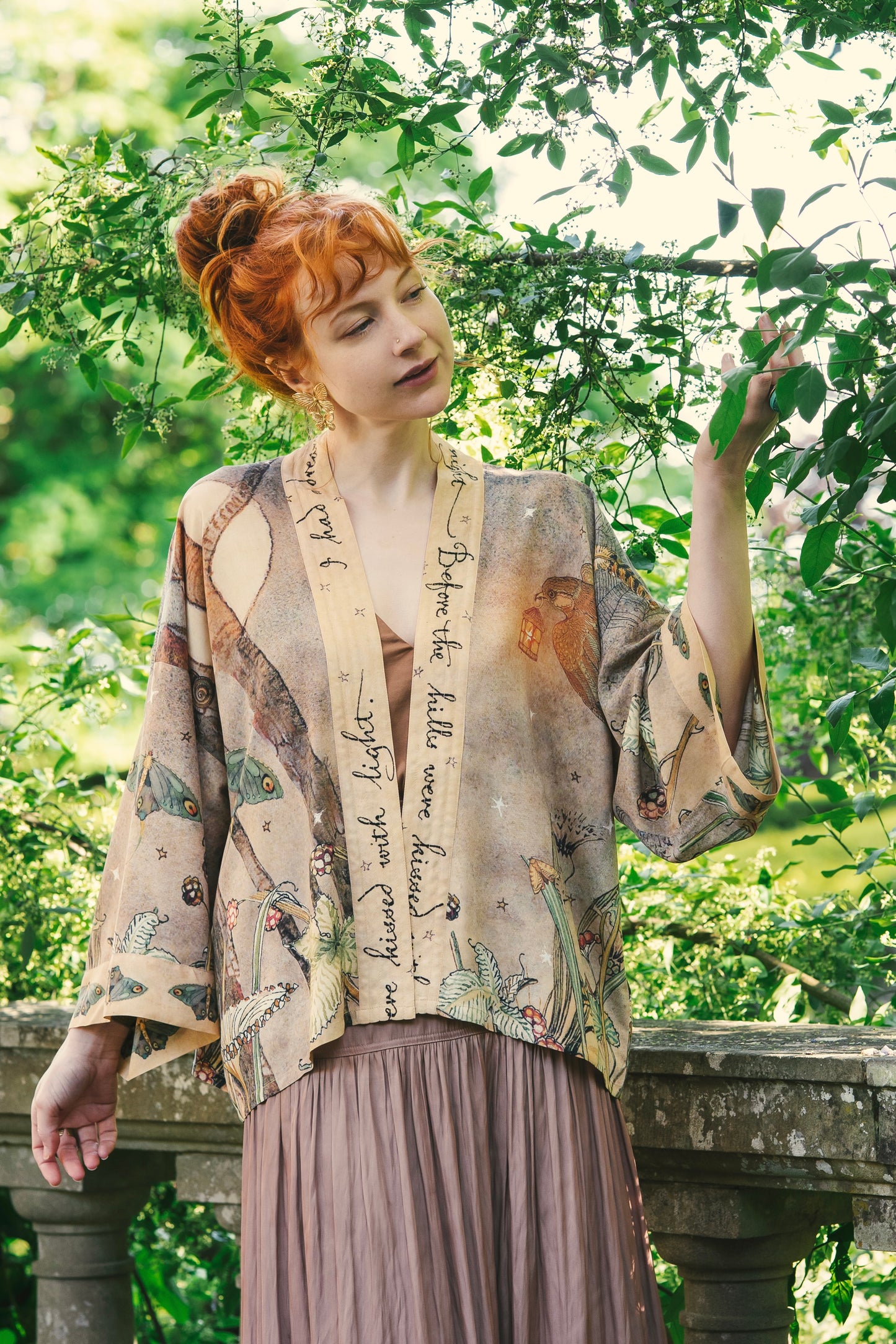 Model wearing an enchanting cropped kimono duster featuring illustrations by Charles van Sandwyck's, crafted from airy bamboo-based viscose with a touch of whimsical magic - Market of Stars