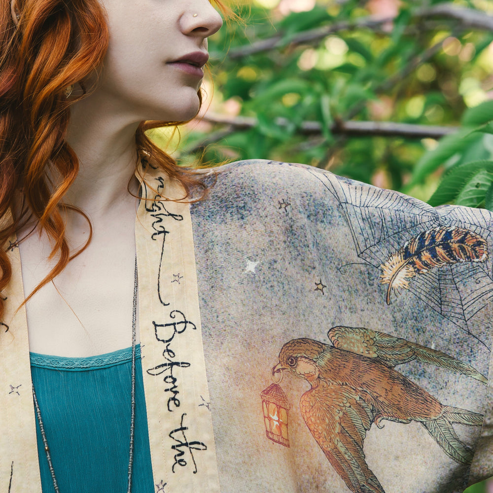 
                  
                    Model wearing an enchanting cropped kimono duster featuring illustrations by Charles van Sandwyck's, crafted from airy bamboo-based viscose with a touch of whimsical magic - Market of Stars
                  
                