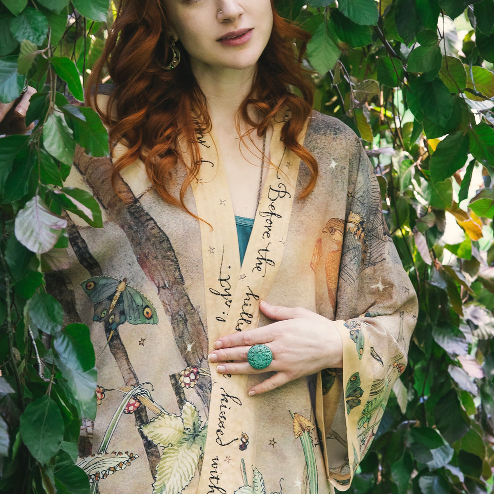 
                  
                    Model wearing an enchanting cropped kimono duster featuring illustrations by Charles van Sandwyck's, crafted from airy bamboo-based viscose with a touch of whimsical magic - Market of Stars
                  
                