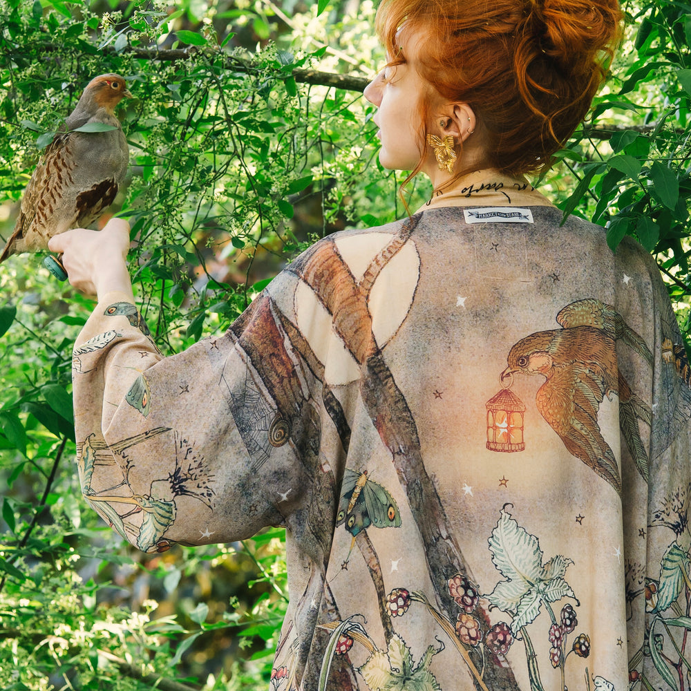 Model wearing an enchanting cropped kimono duster featuring illustrations by Charles van Sandwyck's, crafted from airy bamboo-based viscose with a touch of whimsical magic - Market of Stars