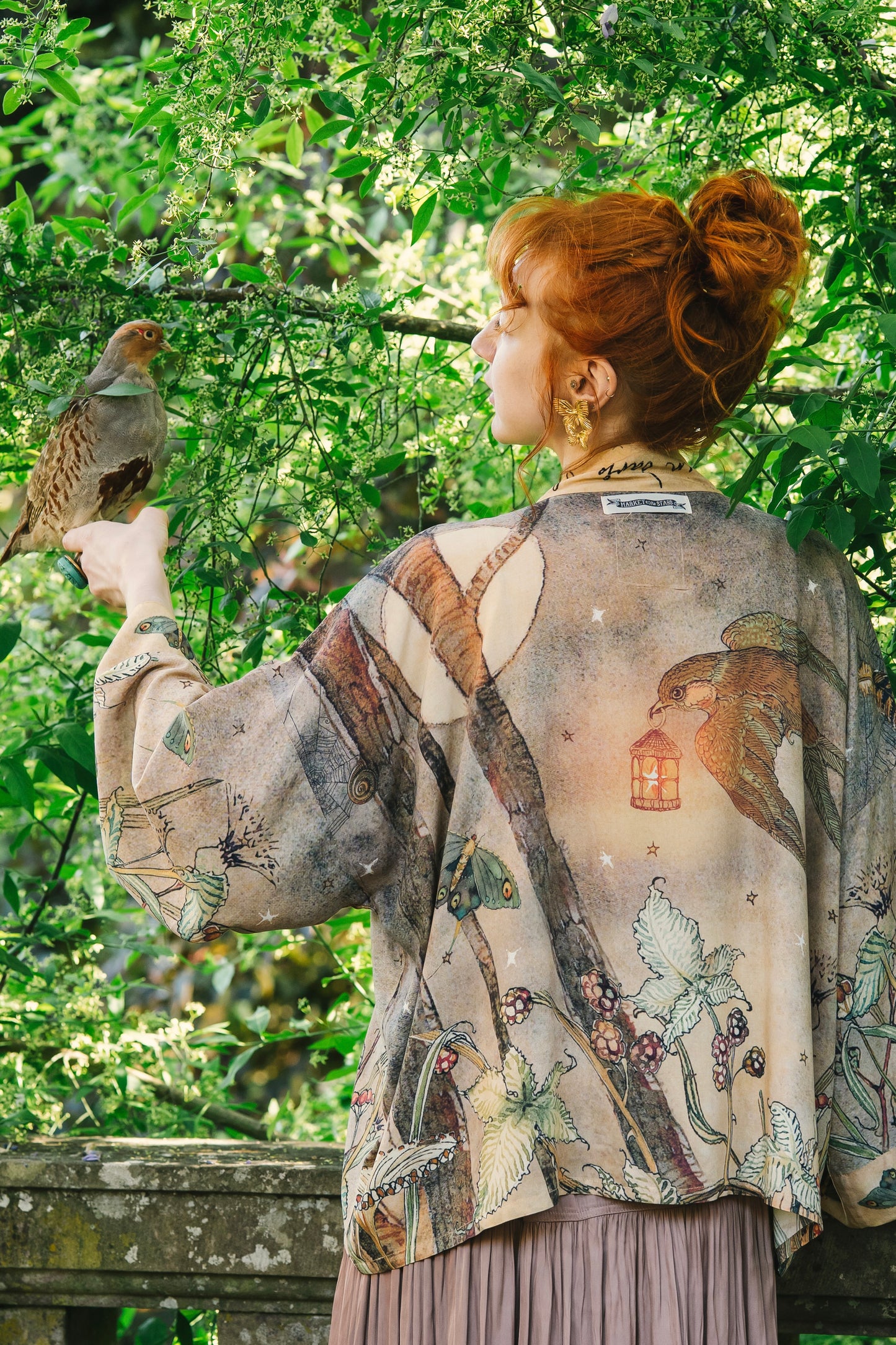 Model wearing an enchanting cropped kimono duster featuring illustrations by Charles van Sandwyck's, crafted from airy bamboo-based viscose with a touch of whimsical magic - Market of Stars