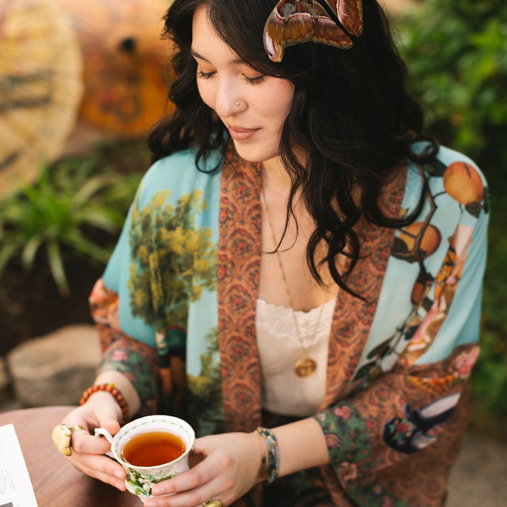
                  
                    Model wearing Peace, Wine & Sunshine Bohéme Slip Dress featuring botanical collages and playful peace, wine and sunshine lettering on the hem – Market of Stars.
                  
                