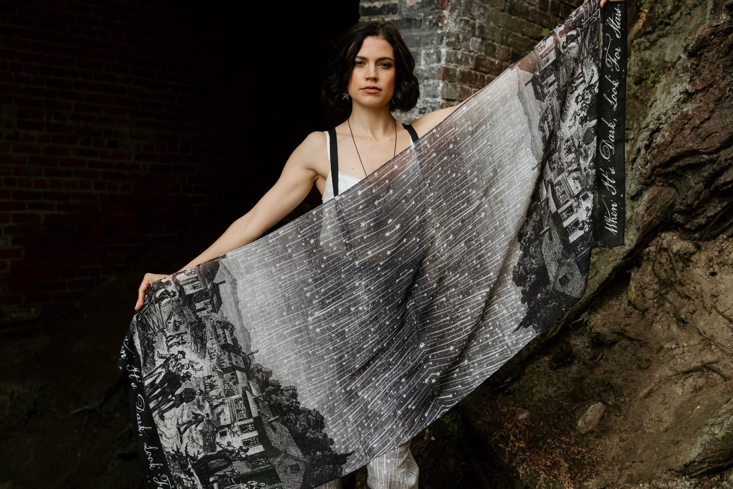 Model wearing the Stargazer Scarf featuring antique night sky illustrations and the quote 