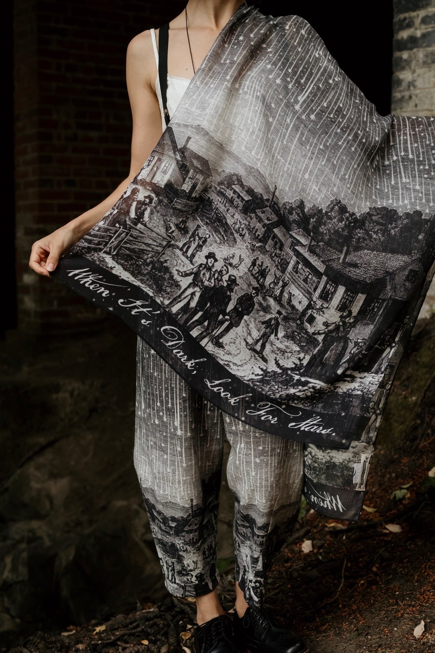 Model wearing the Stargazer Scarf featuring antique night sky illustrations and the quote 