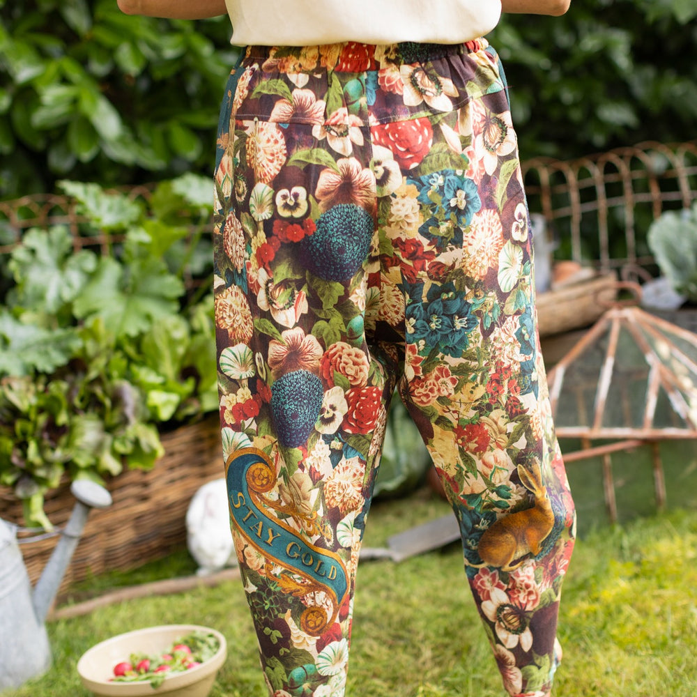 
                  
                    Model wearing Stay Gold linen Artist Pants with lantern hem and floral collage featuring vintage wildflower, bee, and rabbit illustrations – Market of Stars
                  
                