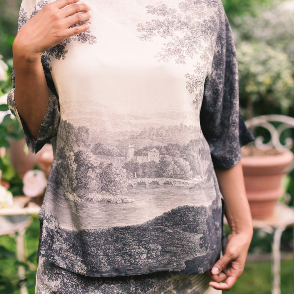 
                  
                    Model wearing the Still I Rise Luxe Tee with wide scoop neck and soft bamboo-based viscose, featuring vintage landscape etching and an inspiring message – Market of Stars
                  
                