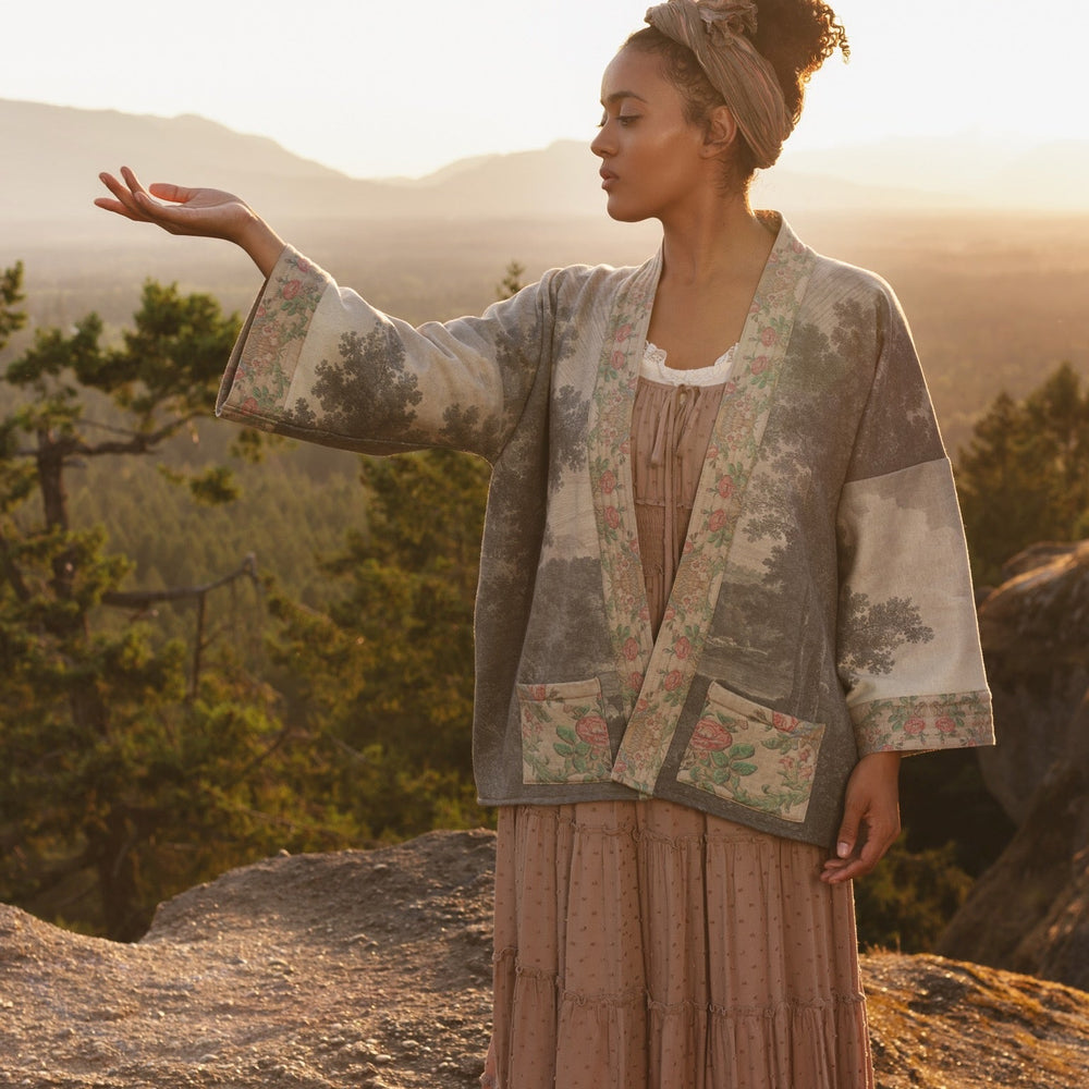 Model wearing the Still I Rise Cottage Cardigan featuring a soft fleece lining and antique landscape etchings in a design inspired by rising strength – Market of Stars