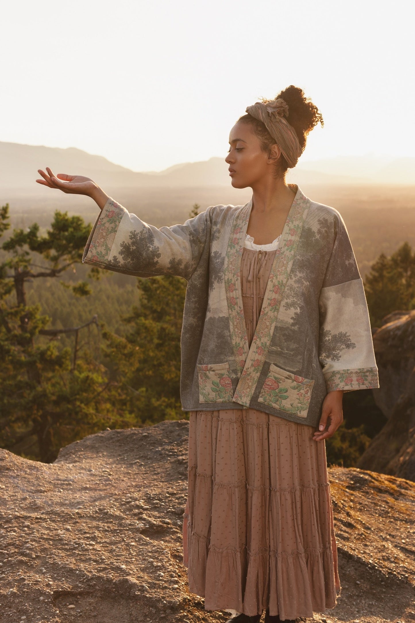 Model wearing the Still I Rise Cottage Cardigan featuring a soft fleece lining and antique landscape etchings in a design inspired by rising strength – Market of Stars
