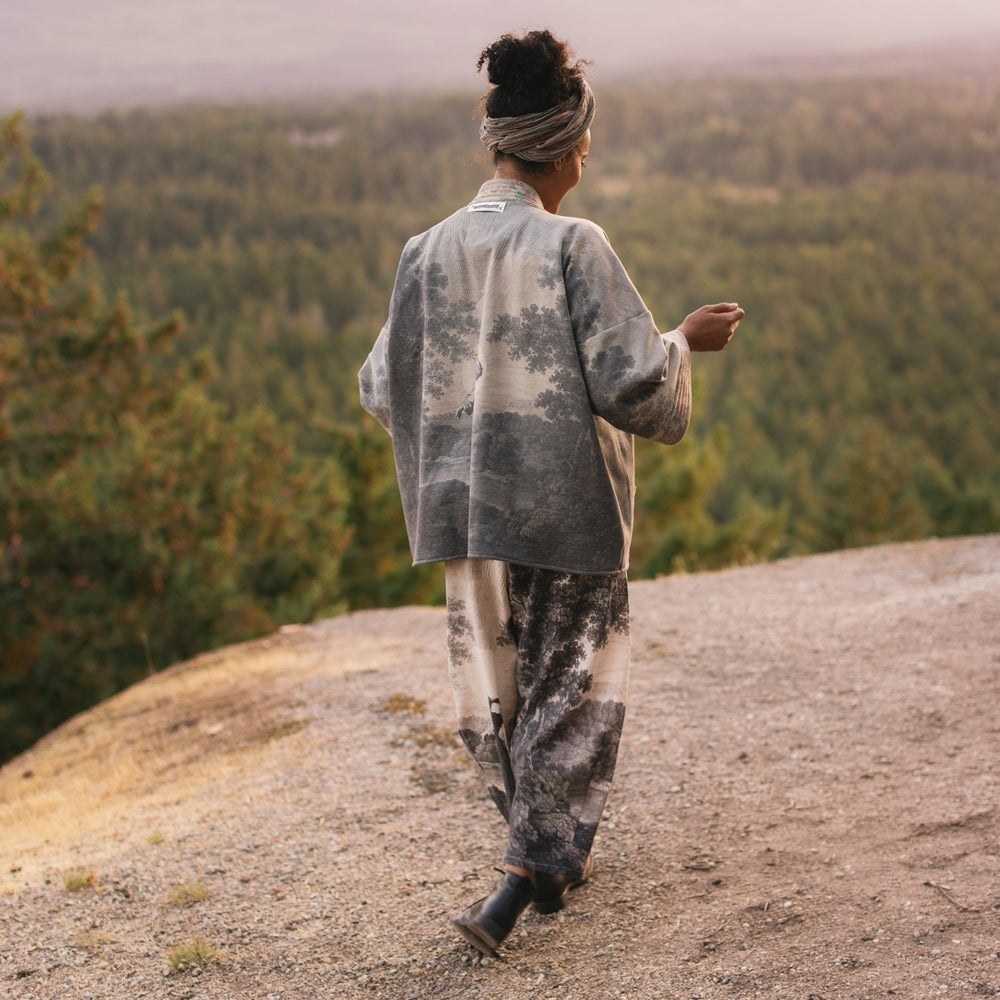 
                  
                    Model wearing the Still I Rise Cottage Cardigan featuring a soft fleece lining and antique landscape etchings in a design inspired by rising strength – Market of Stars
                  
                