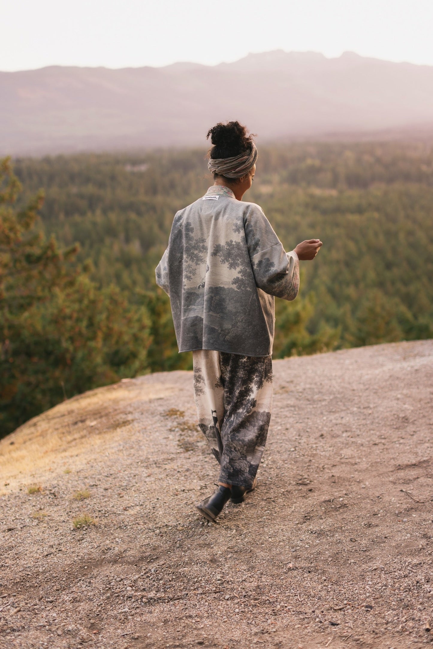 Model wearing the Still I Rise Cottage Cardigan featuring a soft fleece lining and antique landscape etchings in a design inspired by rising strength – Market of Stars