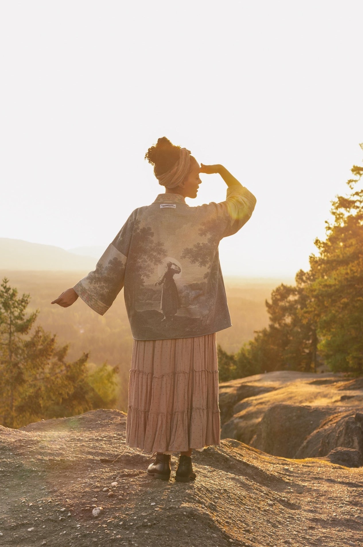 Model wearing the Still I Rise Cottage Cardigan featuring a soft fleece lining and antique landscape etchings in a design inspired by rising strength – Market of Stars