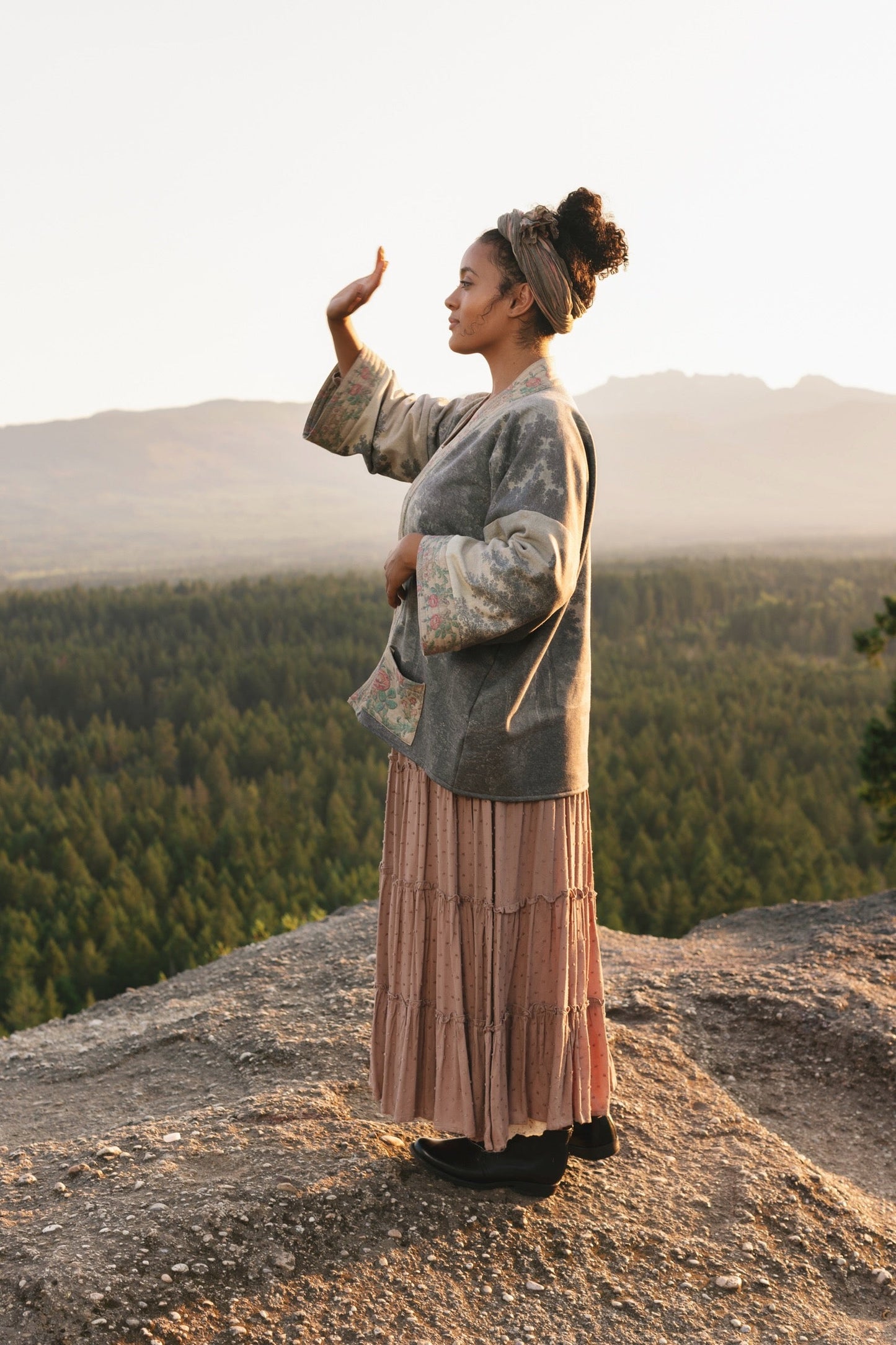 Model wearing the Still I Rise Cottage Cardigan featuring a soft fleece lining and antique landscape etchings in a design inspired by rising strength – Market of Stars