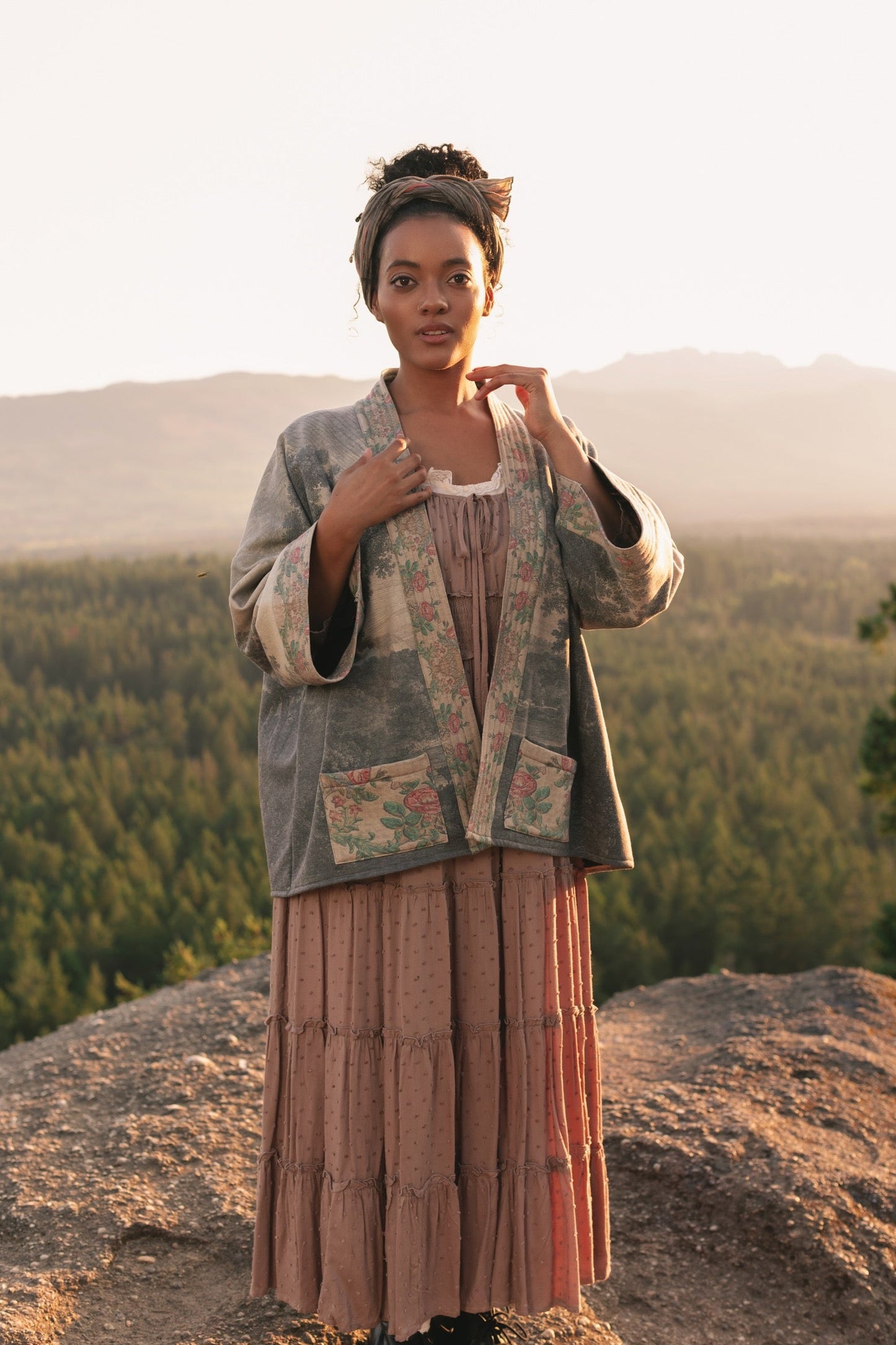 Model wearing the Still I Rise Cottage Cardigan featuring a soft fleece lining and antique landscape etchings in a design inspired by rising strength – Market of Stars
