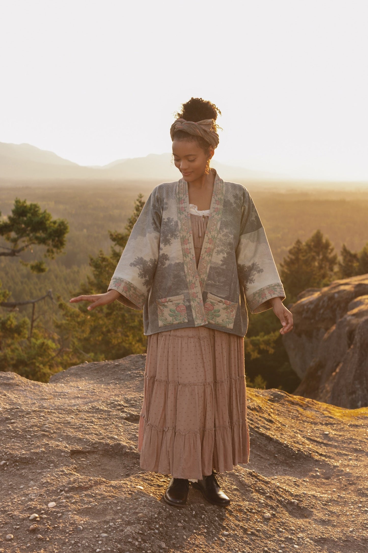 Model wearing the Still I Rise Cottage Cardigan featuring a soft fleece lining and antique landscape etchings in a design inspired by rising strength – Market of Stars