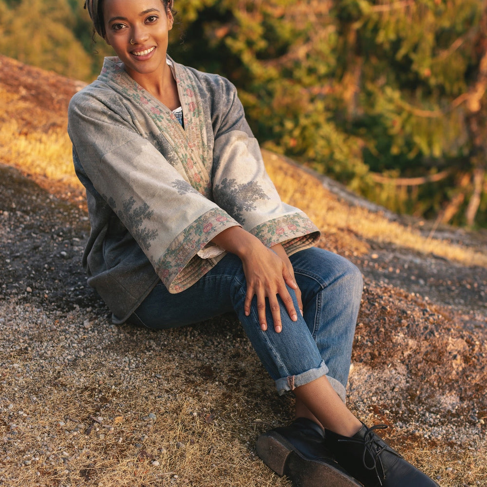 
                  
                    Model wearing the Still I Rise Cottage Cardigan featuring a soft fleece lining and antique landscape etchings in a design inspired by rising strength – Market of Stars
                  
                