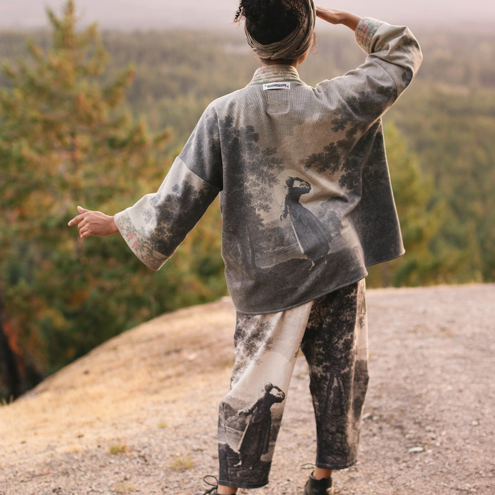 
                  
                    Model wearing the Still I Rise Cottage Cardigan featuring a soft fleece lining and antique landscape etchings in a design inspired by rising strength – Market of Stars
                  
                
