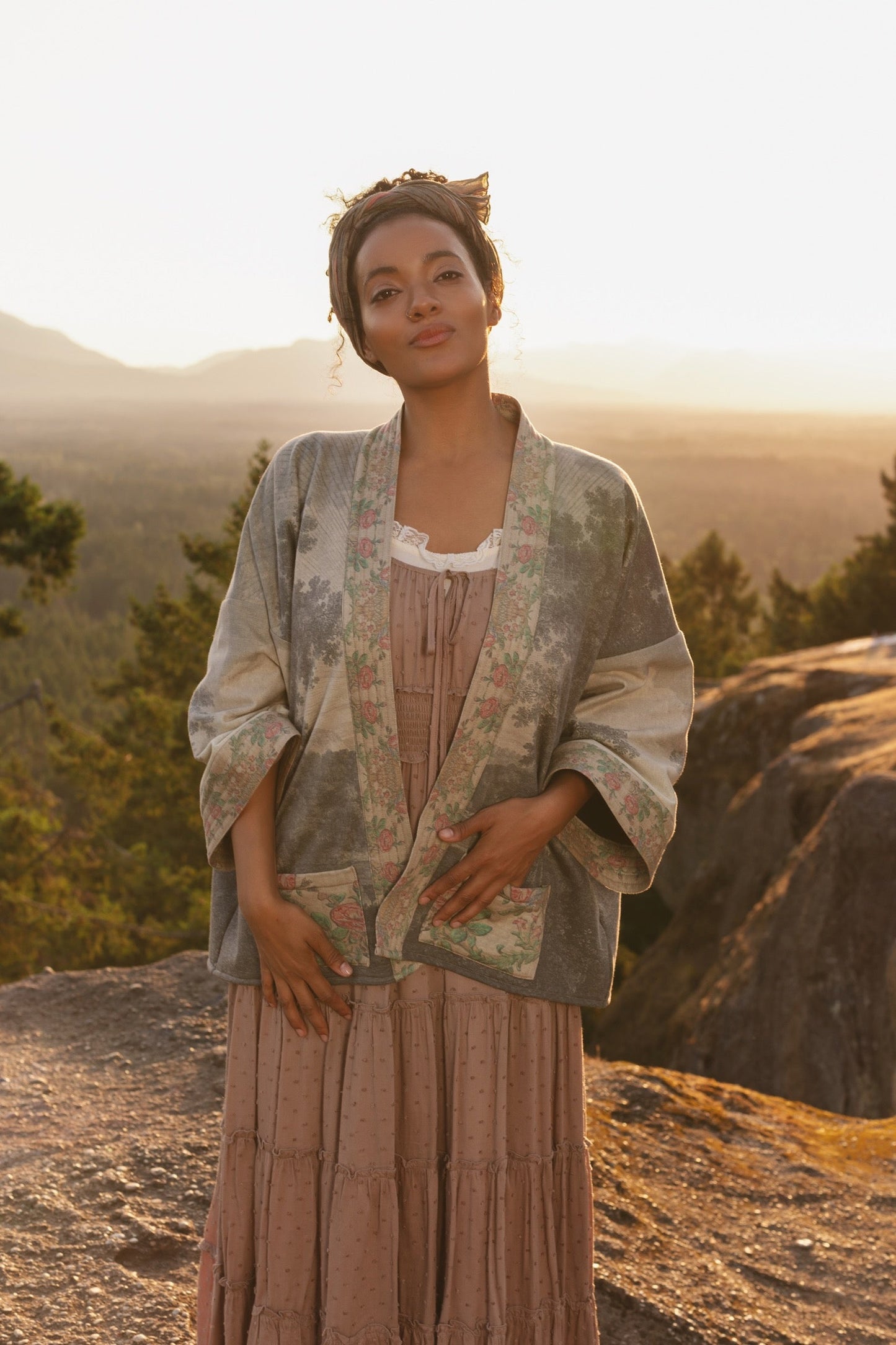 Model wearing the Still I Rise Cottage Cardigan featuring a soft fleece lining and antique landscape etchings in a design inspired by rising strength – Market of Stars