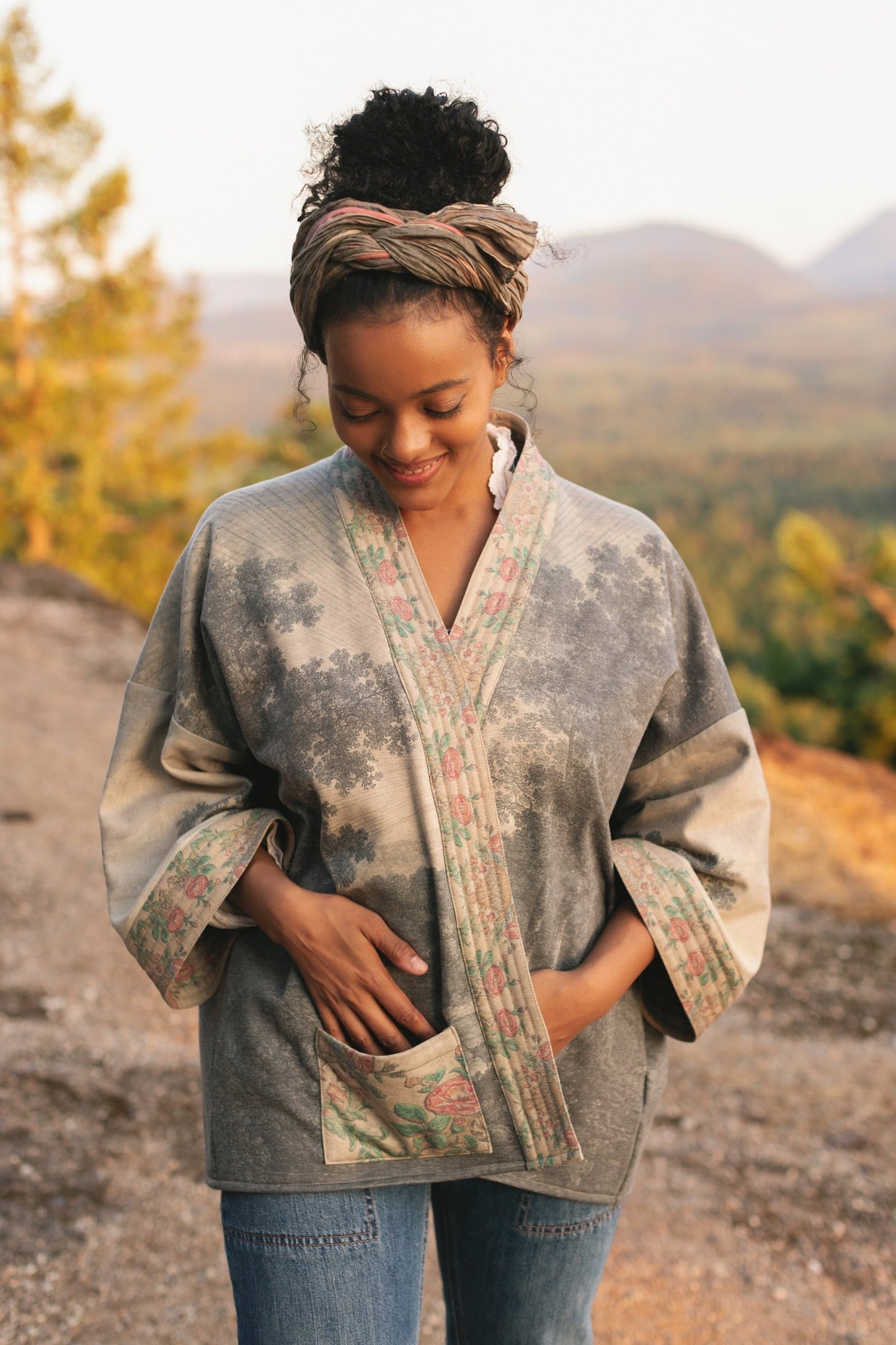Model wearing the Still I Rise Cottage Cardigan featuring a soft fleece lining and antique landscape etchings in a design inspired by rising strength – Market of Stars