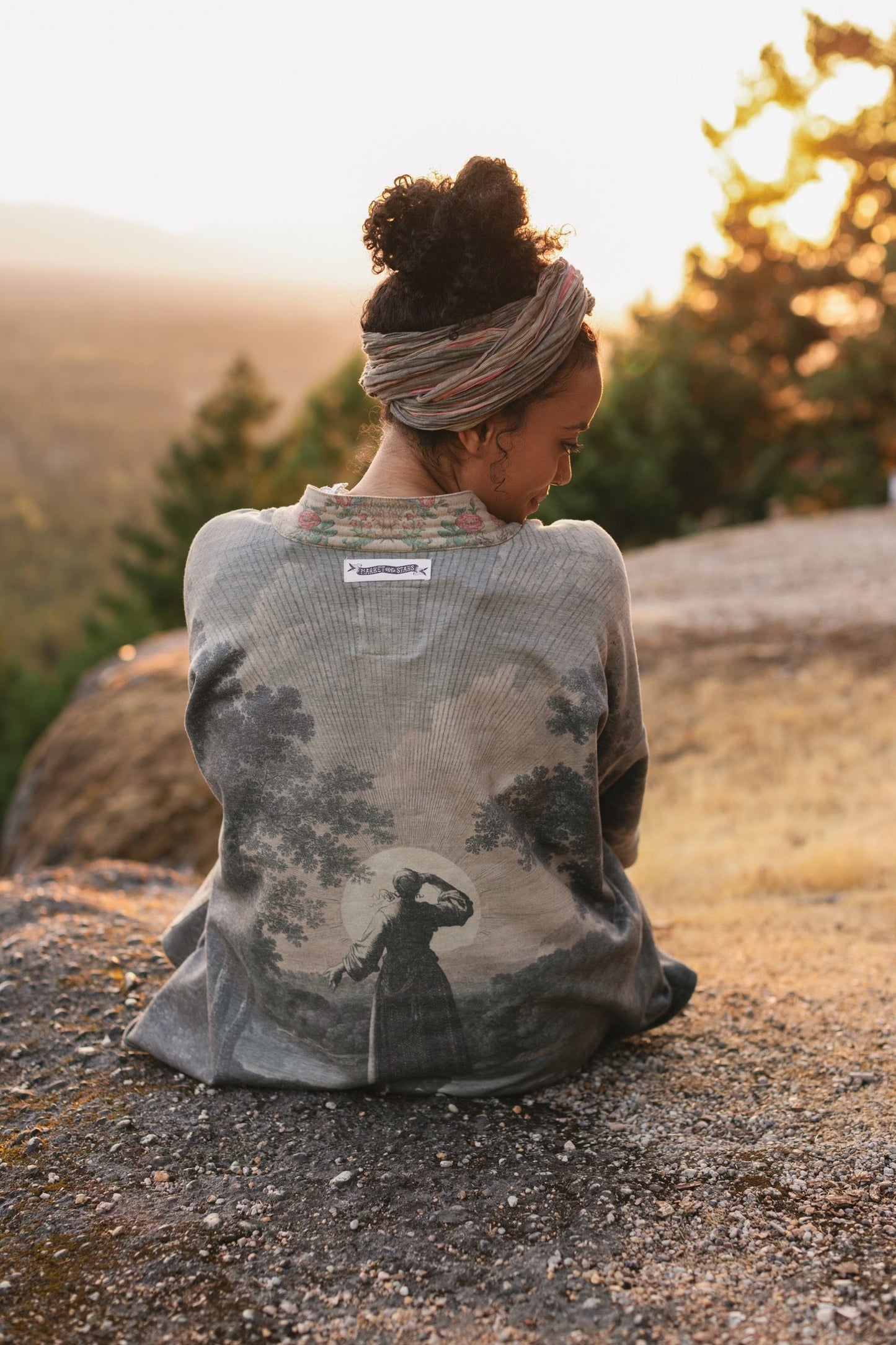 Model wearing the Still I Rise Cottage Cardigan featuring a soft fleece lining and antique landscape etchings in a design inspired by rising strength – Market of Stars