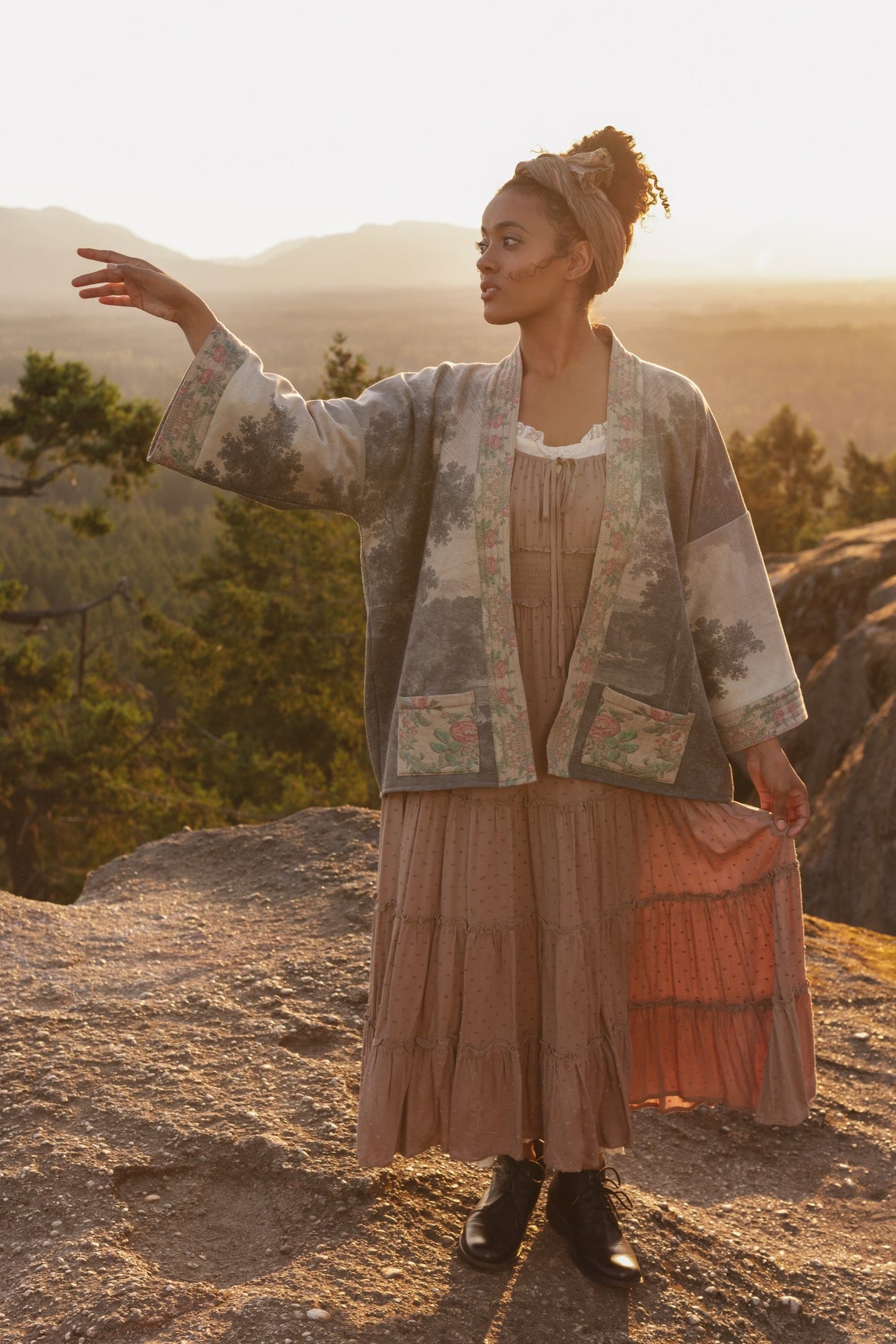 Model wearing the Still I Rise Cottage Cardigan featuring a soft fleece lining and antique landscape etchings in a design inspired by rising strength – Market of Stars