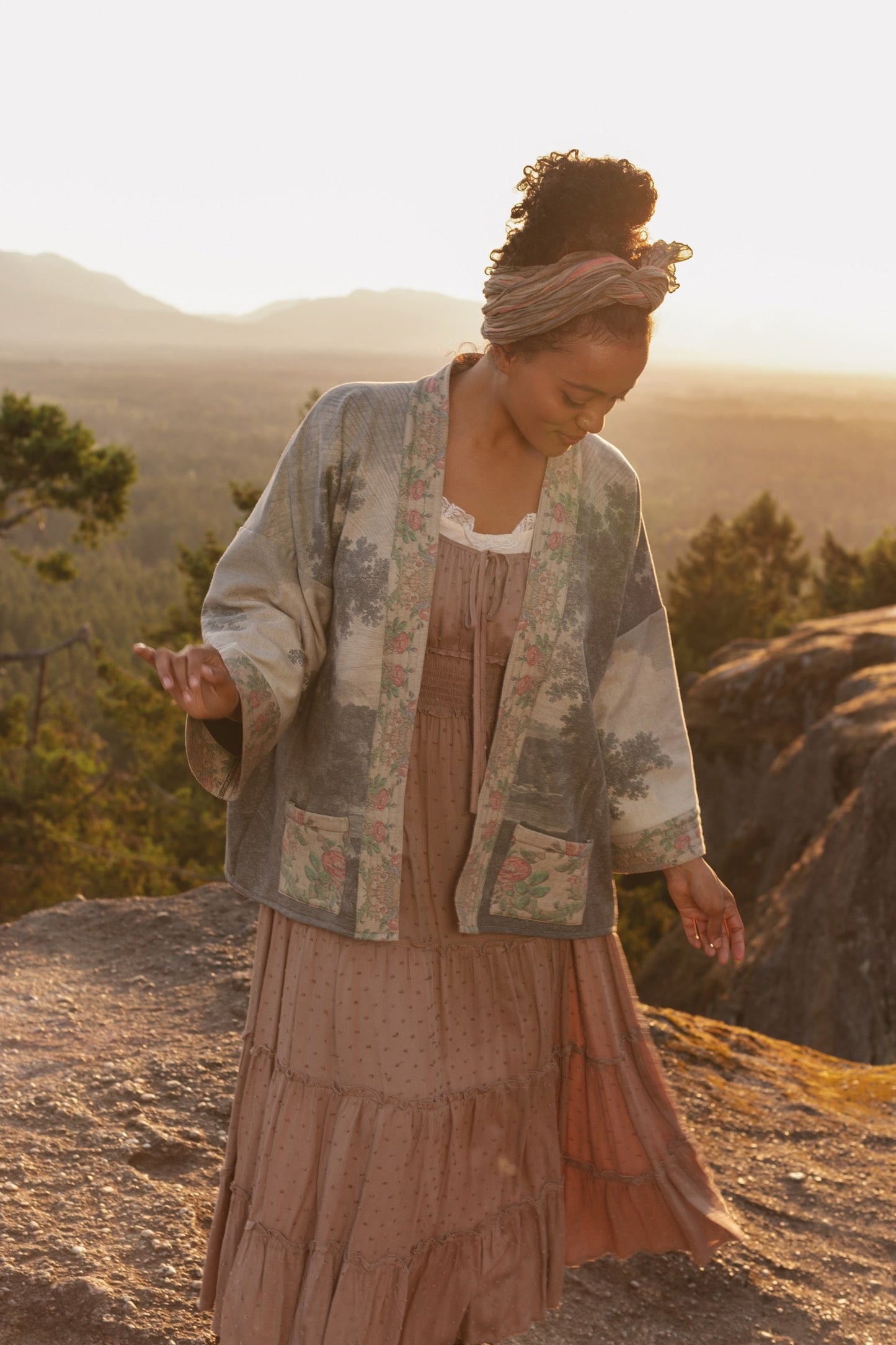 Model wearing the Still I Rise Cottage Cardigan featuring a soft fleece lining and antique landscape etchings in a design inspired by rising strength – Market of Stars