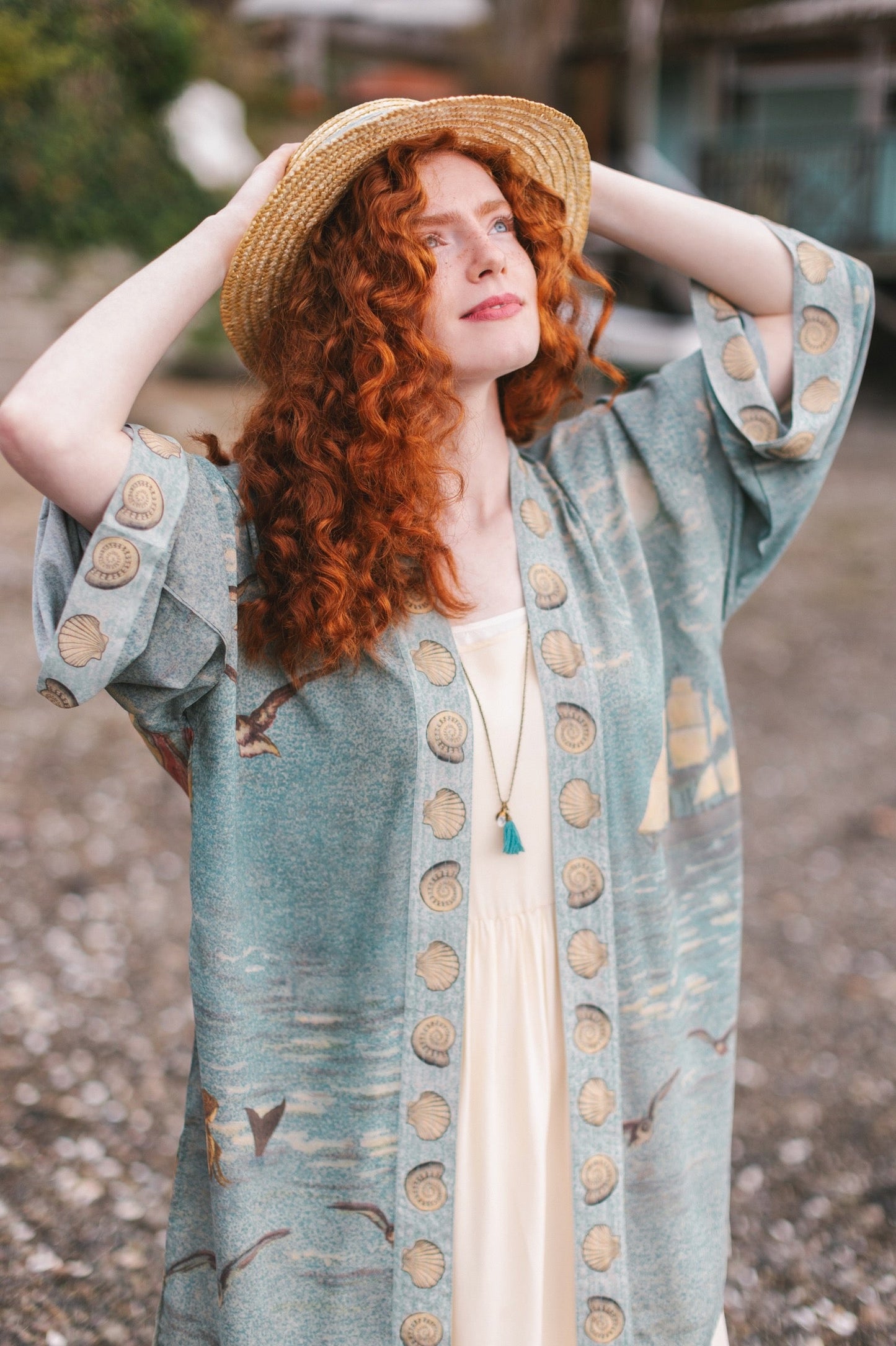Lightweight duster featuring antique sunrise sky, mermaid, shell, and soaring birds artwork, shown on model at the beach – Market of Stars