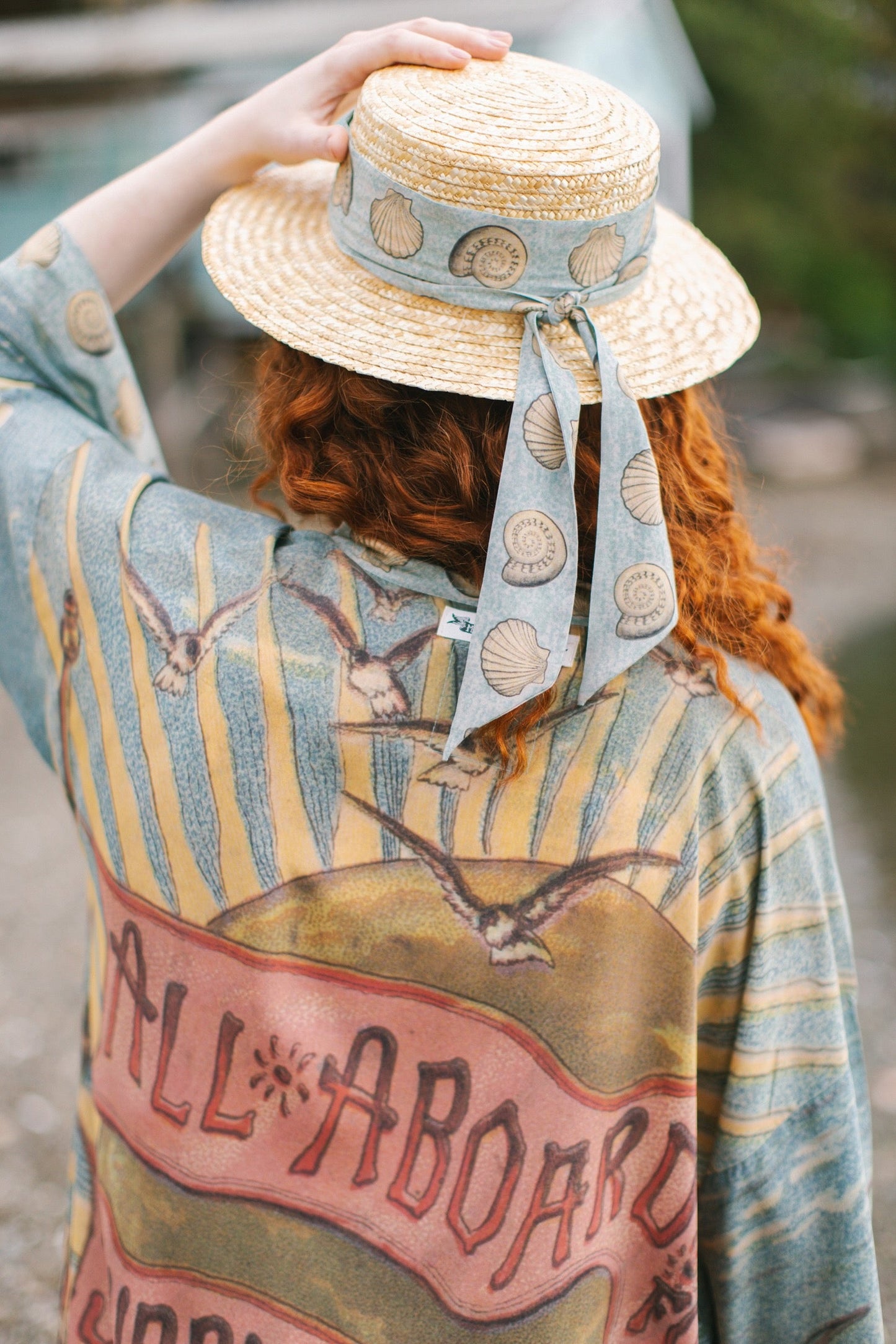 Lightweight duster featuring antique sunrise sky, mermaid, shell, and soaring birds artwork, shown on model at the beach – Market of Stars