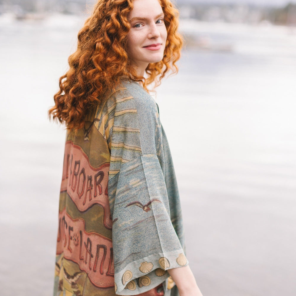 
                  
                    Lightweight duster featuring antique sunrise sky, mermaid, shell, and soaring birds artwork, shown on model at the beach – Market of Stars
                  
                